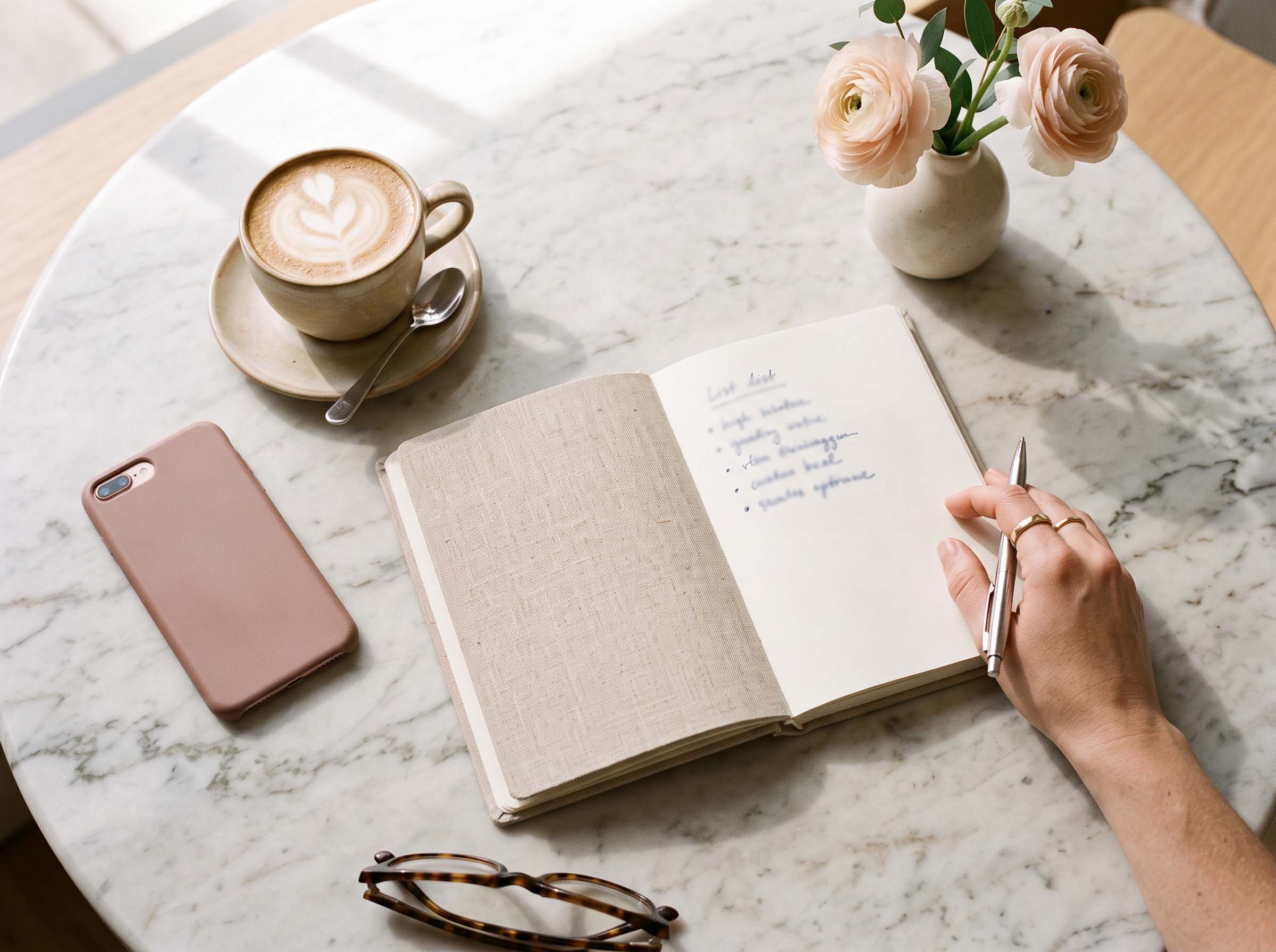 Notebook, coffee cup and phone on a cafe table where a woman plans a second date