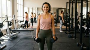 Mulher segurando halteres na academia — guia de treino de força para mulheres iniciantes