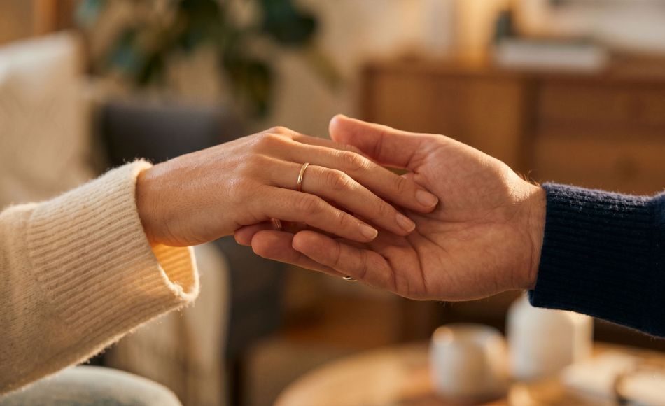 A woman's hand gently resting in a man's hand in soft warm light, expressing romantic love through touch