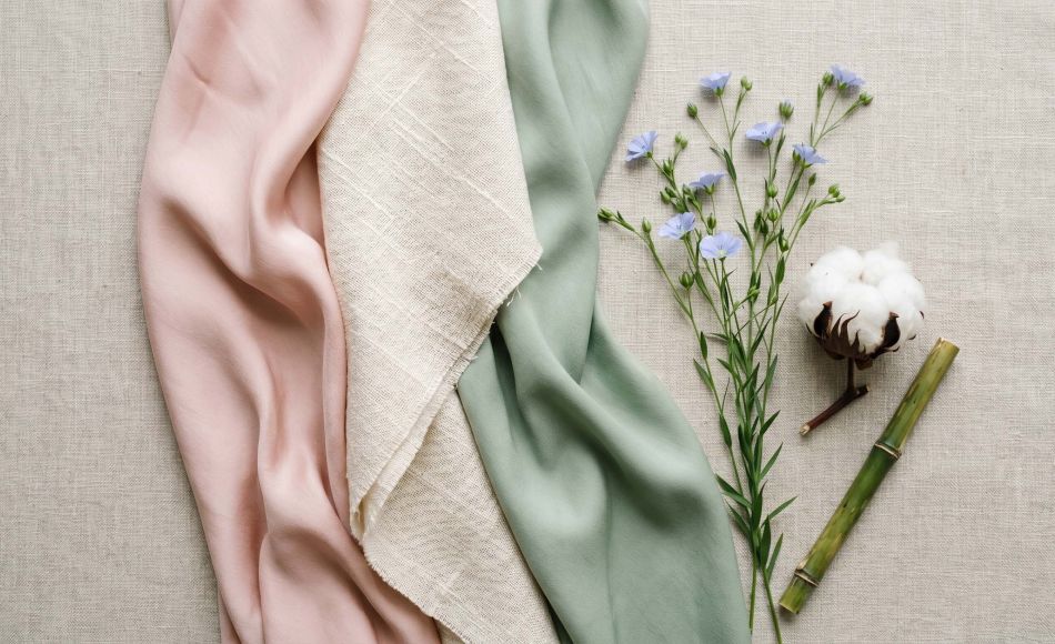 Silk, cotton, and bamboo fabric swatches arranged in a feminine flat-lay representing the best fabrics for women's intimate comfort