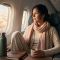 Mujer con suaves capas de algodón y lana merino descansando cómodamente en un asiento junto a la ventana de un avión durante un vuelo largo