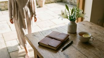 An elegant journal and pen on a wooden table representing feminine reflection and personal growth.