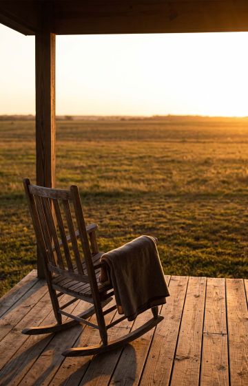 Empty porch chair overlooking an open field at golden hour, representing the midlife years