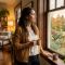 Una mujer pensativa mirando por una ventana en un hogar cálido.