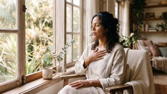 Mulher perto de uma janela respirando lentamente para acalmar um sistema nervoso hiperativo