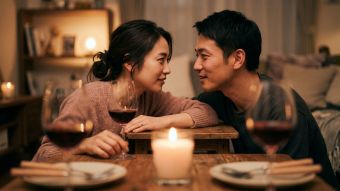 自宅でキャンドルの灯りの中、温かな食事を楽しみながら笑い合い、自然に寄り添うカップル