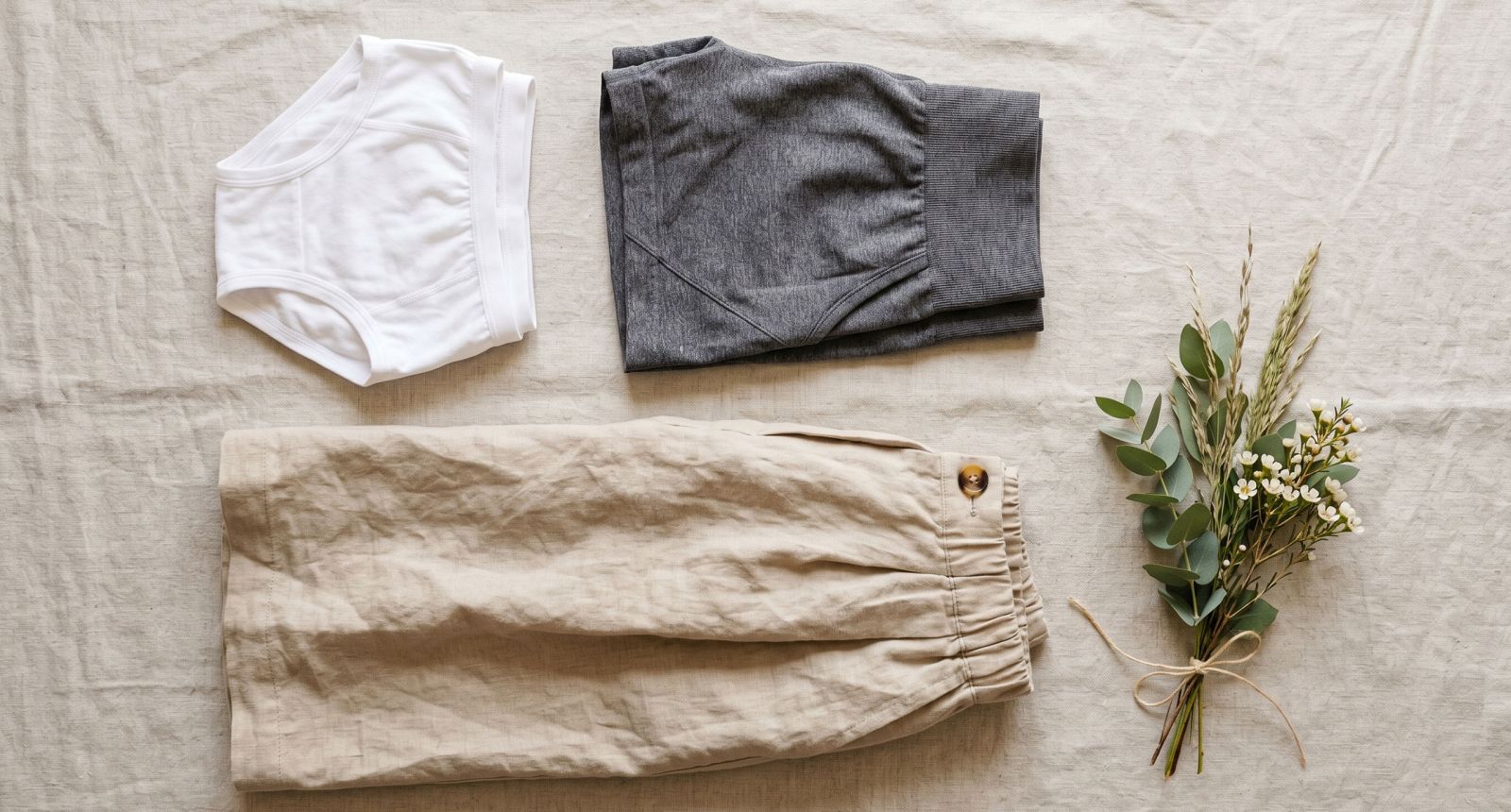 Flat-lay of cotton underwear, linen skirt, and activewear shorts on a neutral surface