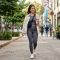 Una mujer elegante camina por una acera urbana con ropa activewear verde oliva y una chaqueta beige.