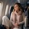 Woman in soft cotton and merino layers resting comfortably in an aircraft window seat on a long-haul flight
