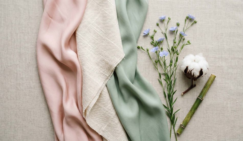 Silk, cotton, and bamboo fabric swatches arranged in a feminine flat-lay representing the best fabrics for women's intimate comfort
