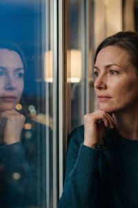 Woman sitting alone looking out a window in quiet reflection