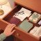 Illustrated open nightstand drawer with personal keepsakes and a woman's hand resting on the edge