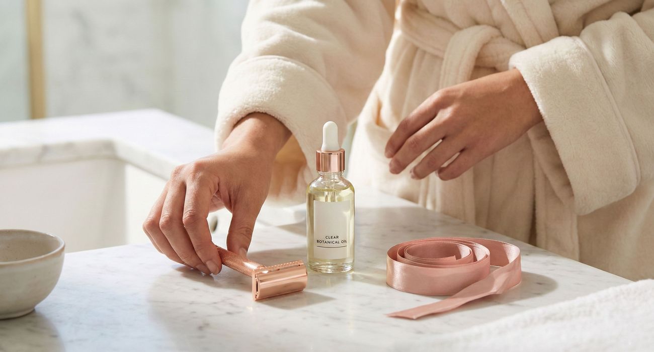 Herramientas elegantes y aceites calmantes para la depilación íntima femenina.