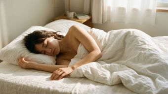 柔らかな朝の光の中で白いリネンに包まれて安らかに休む女性