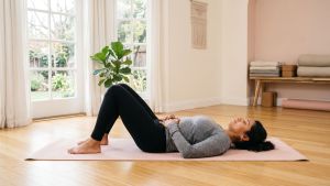 Mujer practicando ejercicios de suelo pélvico sobre una esterilla de yoga en una habitación luminosa y espaciosa