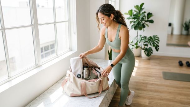 Mujer con ropa deportiva clara dejando una bolsa de gimnasio tras entrenar, luz natural
