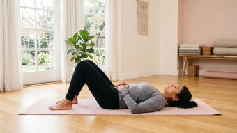 Mujer practicando ejercicios de suelo pélvico sobre una esterilla de yoga en una habitación luminosa y espaciosa