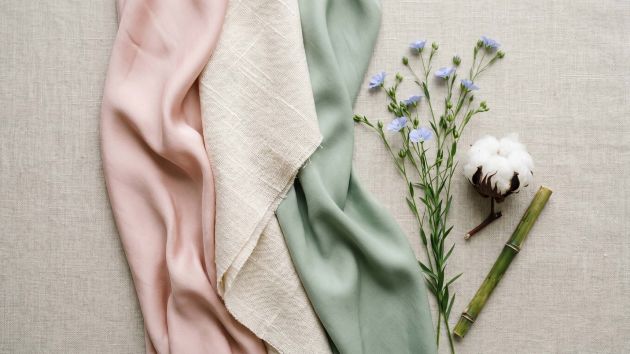 Muestras de tejidos de seda, algodón y bambú dispuestas en una composición femenina tipo flat lay que representa los mejores tejidos para la comodidad íntima femenina