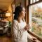 A thoughtful woman looking out a window in a warm home setting.