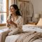 Mujer relajándose en la cama, representando los hábitos y preferencias de ropa para dormir de las mujeres