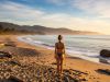 Una playa naturista tranquila con viajeros disfrutando del mar en un ambiente relajado.